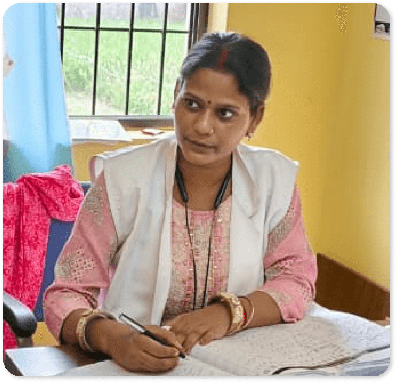 South Asian female Community Health Officer working at her desk with a notebook